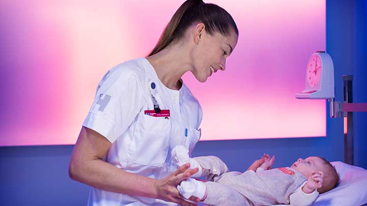 Nurse weighing baby in softly lit room - healthcare lights