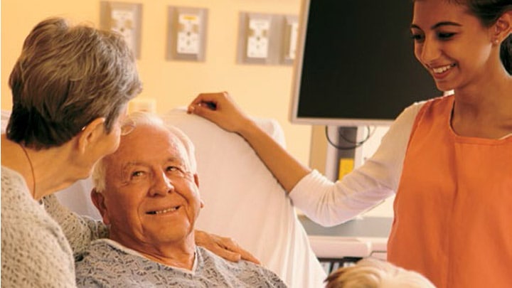 Nurse in softly lit room listing to patient’s heart with patient - hospital lighting