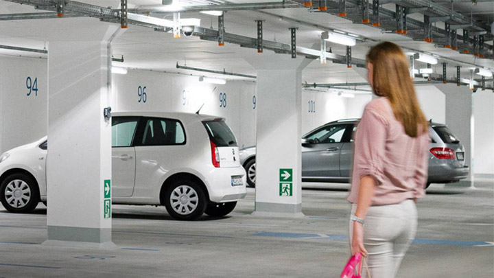 Woman walks to car in well-lit underground car park 