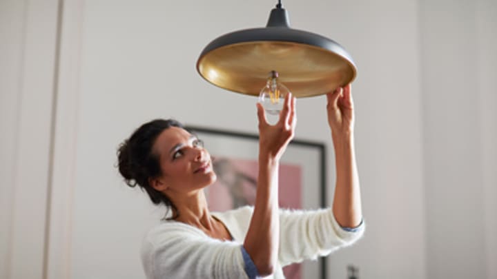 Woman screwing in a consumer light bulb at home