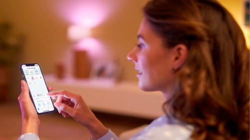 Woman controlling the lights in her living rooms with her smartphone