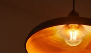 "Vintage-style LED filament bulb in pendant lamp, emitting warm golden glow, showcasing energy-efficient nostalgic lighting for cozy home ambiance."